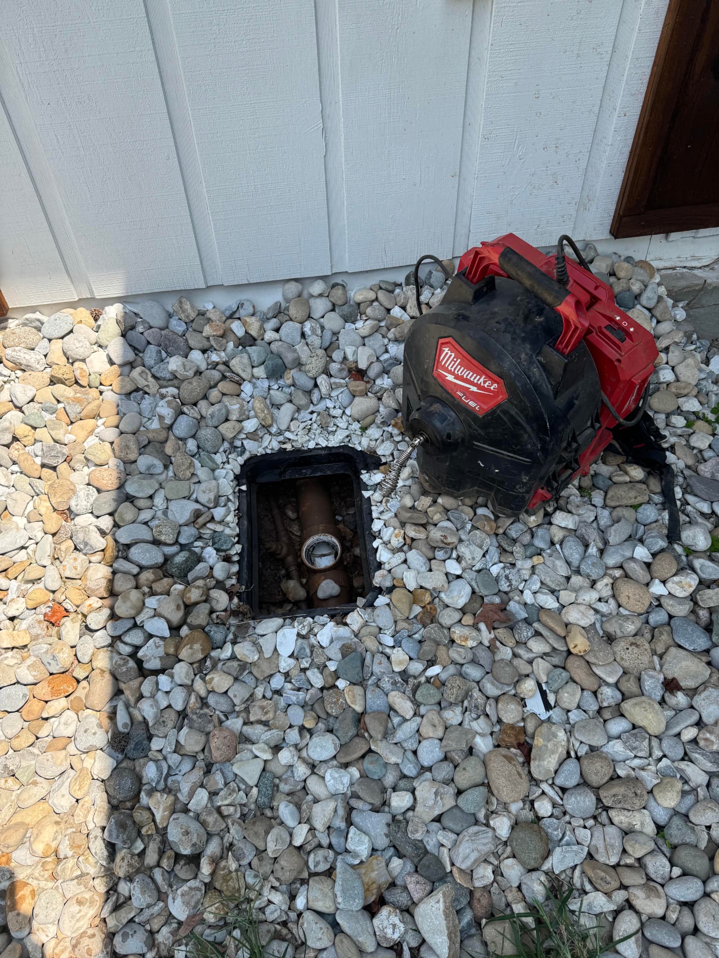 Drain cleaning machine cabling an outdoor sewer cleanout beside a home in Gadsden, Alabama