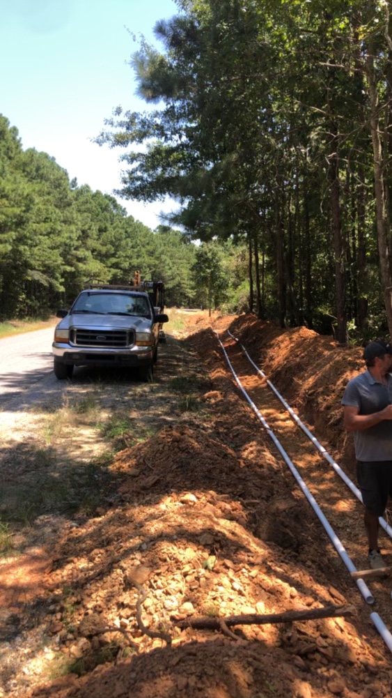 New water main line being run in a long roadside trench by M&B Plumbing and Septic in Etowah County, Alabama
